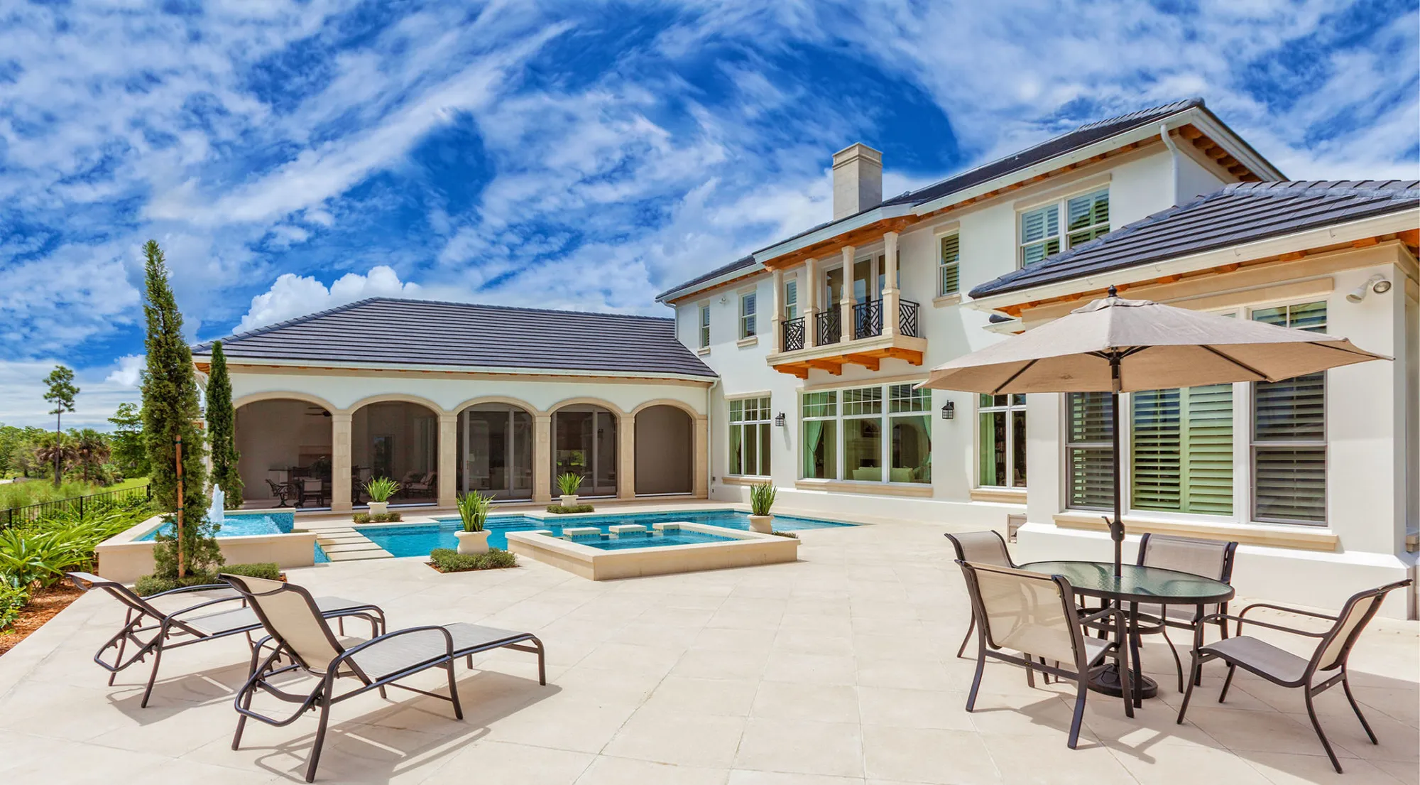 Backyard pool and patio behind a two-story home